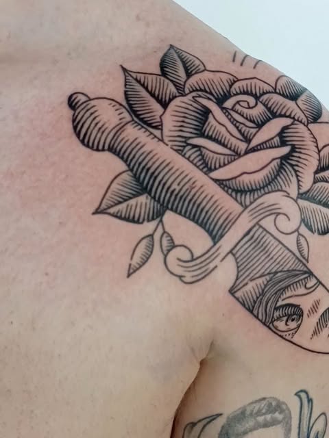 Black linework tattoo of a hand holding a rose